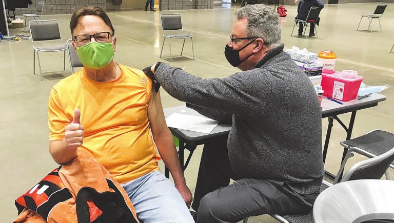 Tim Tyra of Greendale, above, gets his first vaccination shot Thursday at the Lawrenceburg Event Center. Giving the shot is Bruce Canfield, a volunteer who is retired after working at the hospital in Dearborn County for 45 years. Melvin D. Dunaway, right, of Aurora, gets his shot from Deena Gindling, who is a nurse with Beacon Orthopedics. PHOTOS BY MARC EMRAL/JOURNAL-PRESS