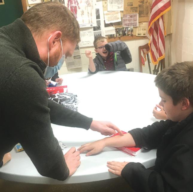 Dr. Christopher Walcott demonstrates how to apply a bandage with second grader Cash Hammers. TIFFANY CLARK/Rising Sun Recorder