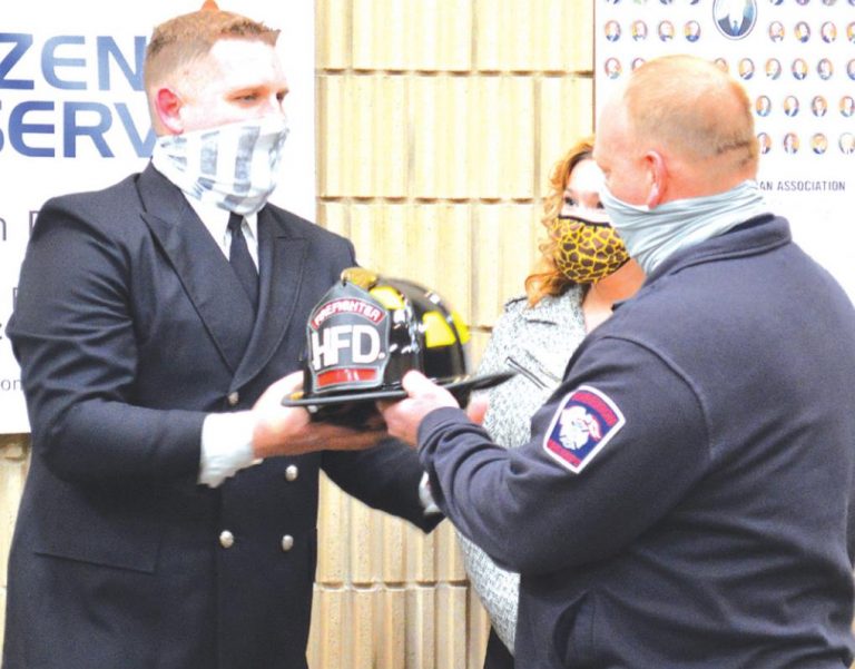 Harrison Fire Capt. Cam Kugler, right, hands new Harrison firefighter Andrew Browning his new helmet. Behind Kugler is his wife Kylie. HALIE BARGER/THE HARRISON-PRESS
