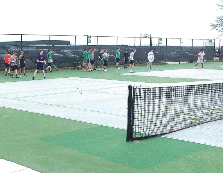 Members of Harrison’s boys tennis team practice volleys, as they avoid rolling tennis balls across the court, at the school March 17. PHOTO BY DICK MALONEY