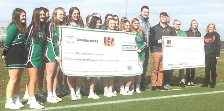 Harrison cheerleaders and school officials display the checks from the Cincinnati Bengals for the school’s new synthetic turf football field. PHOTO BY DICK MALONEY