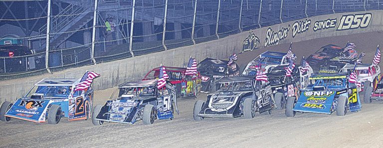 Flags fly for the parade lap of Saturday night’s 10th annual Merrill Downey Memorial 44-lap feature race for UMP Modifieds at Lawrenceburg Speedway. Tennessee driver Ricky Arms was the surprise winner after early leaders Tyler Nicely and Nick Hoffman crashed. TIM THOMAS/L’BURG SPEEDWAY